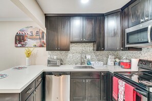 A modern kitchen with dark wood cabinets, a stainless steel dishwasher, a microwave, and a stove.