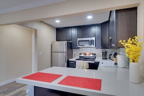 A modern kitchen with dark cabinets, stainless steel appliances, and a white countertop.