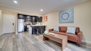 A modern living room with a brown leather sofa, a wooden coffee table, and a kitchen in the background. - 2 Mi to Dtwn Pleasanton Condo w/ Pool Access (Pleasanton)