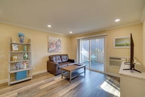 A living room with a brown leather sofa, a wooden coffee table, and a bookshelf with decorative items. - Couple's Retreat 2 Mi to Dtwn Pleasanton! (Pleasanton)