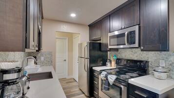 A modern kitchen with stainless steel appliances, a microwave, a stove, and a refrigerator.