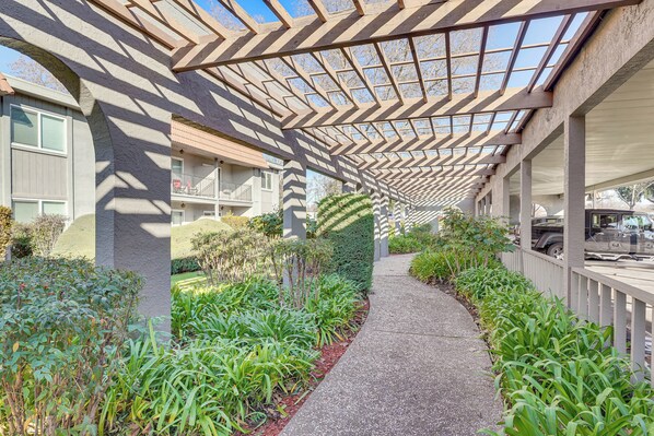 A covered walkway with a patterned ceiling, surrounded by greenery and a gravel path. - Couple's Retreat 2 Mi to Dtwn Pleasanton! (Pleasanton)