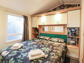 A bedroom with a bed, a window, curtains, a mirror, and built-in storage cabinets. - Granada at Avalon Eco Farm (Cambridge)
