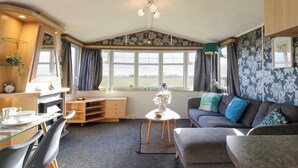 A cozy room with a dining area, a sofa, and a view of the outdoors. - Granada at Avalon Eco Farm (Cambridge)