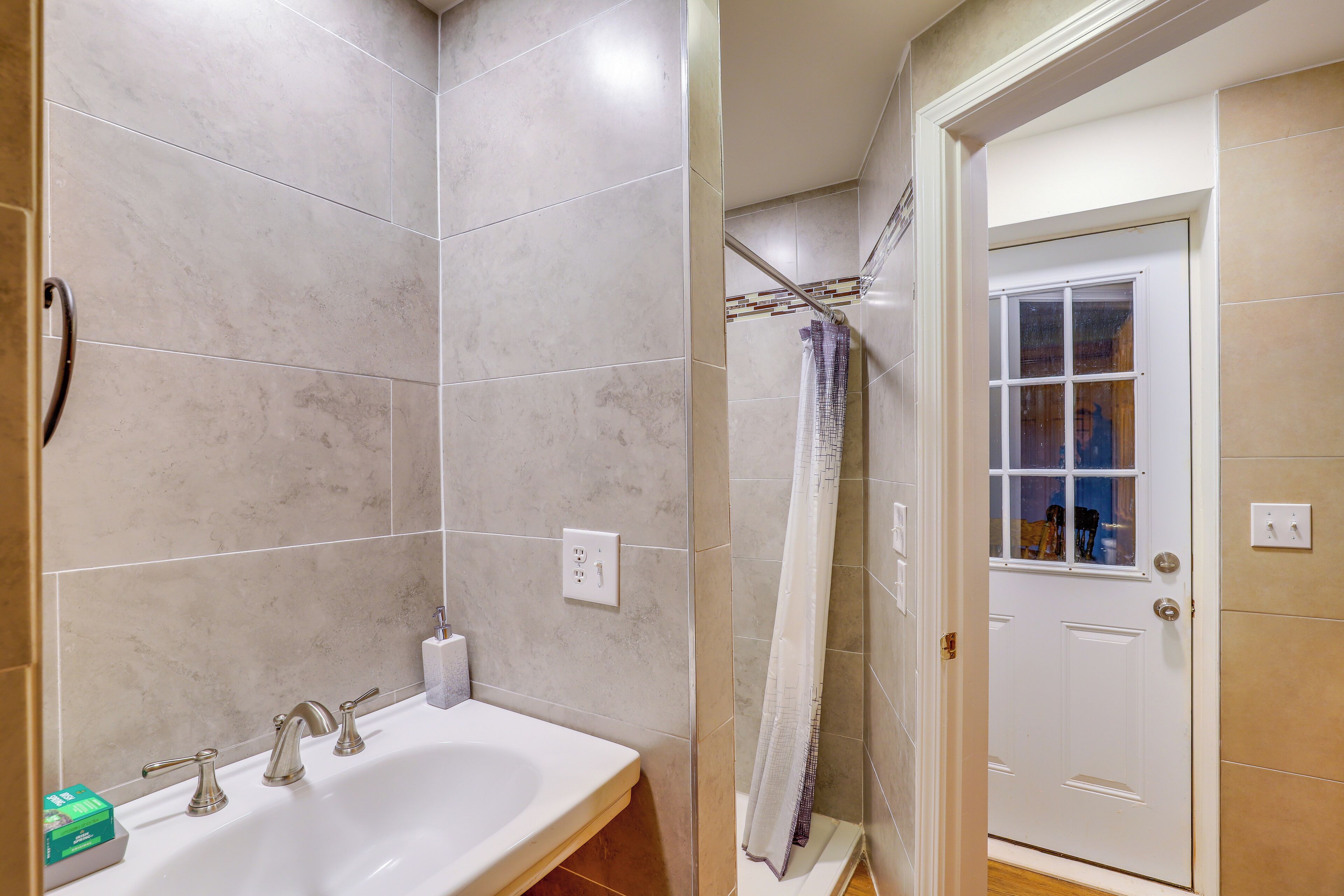 A bathroom with a white sink, two faucets, and a shower curtain.