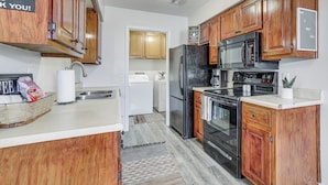 A compact kitchen with wooden cabinets, a black refrigerator, a microwave, and a stove. - Visit Route 66! Pet-friendly Joplin Gem w/ Yard (Joplin)