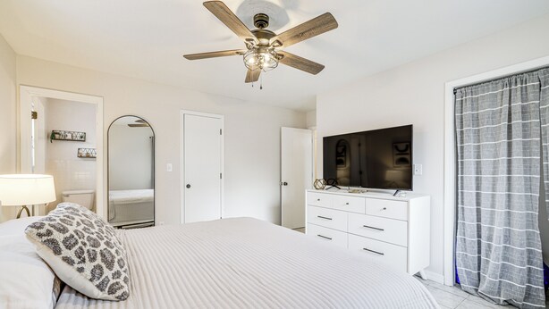 A bedroom with a bed, a ceiling fan, a dresser, a TV, and a window with curtains. - Visit Route 66! Pet-friendly Joplin Gem w/ Yard (Joplin)