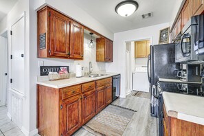 Eine Küche mit Holzschränken, einem Edelstahlkühlschrank und einer Mikrowelle.