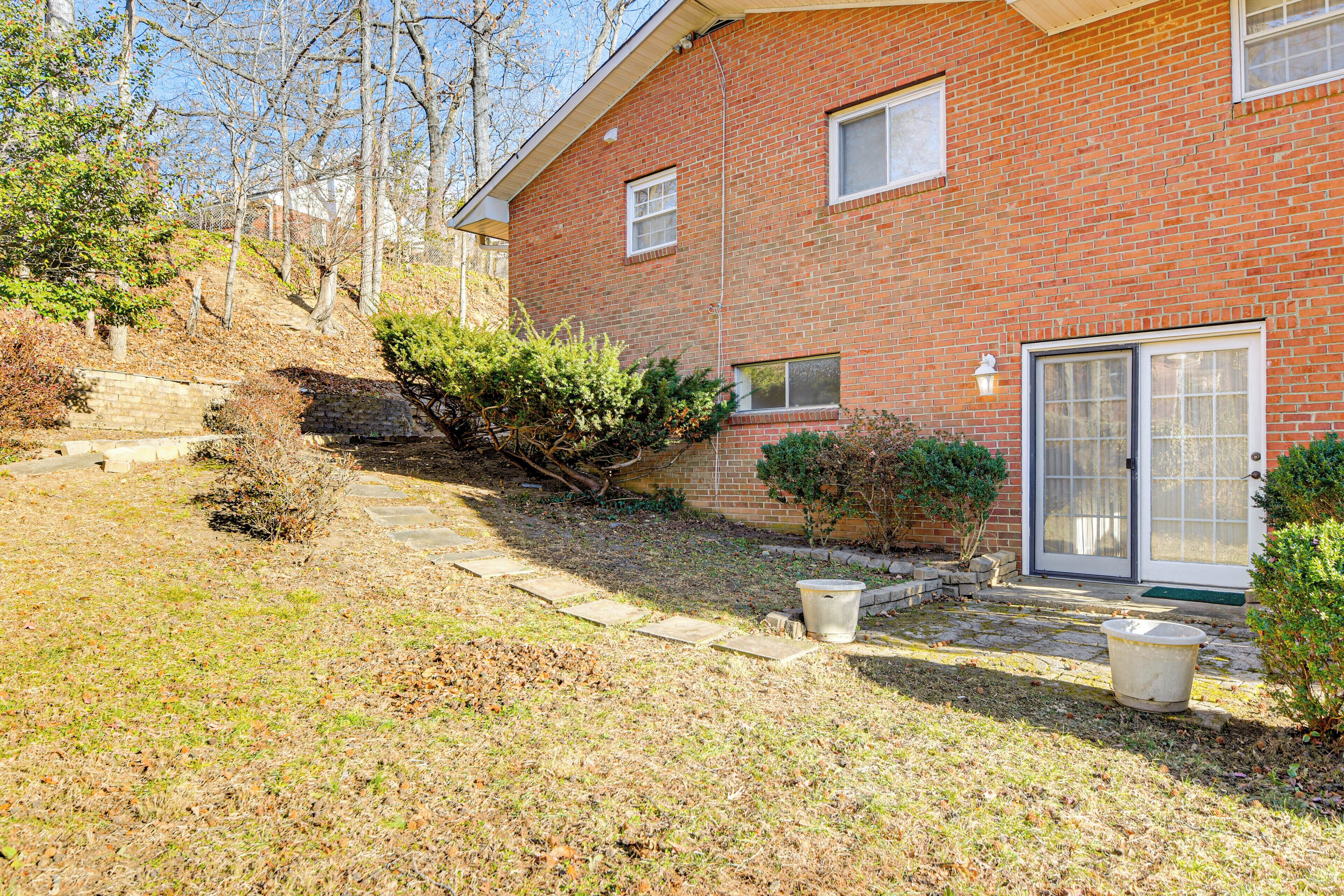 A brick house with a front yard, a stone pathway, and a small bush.