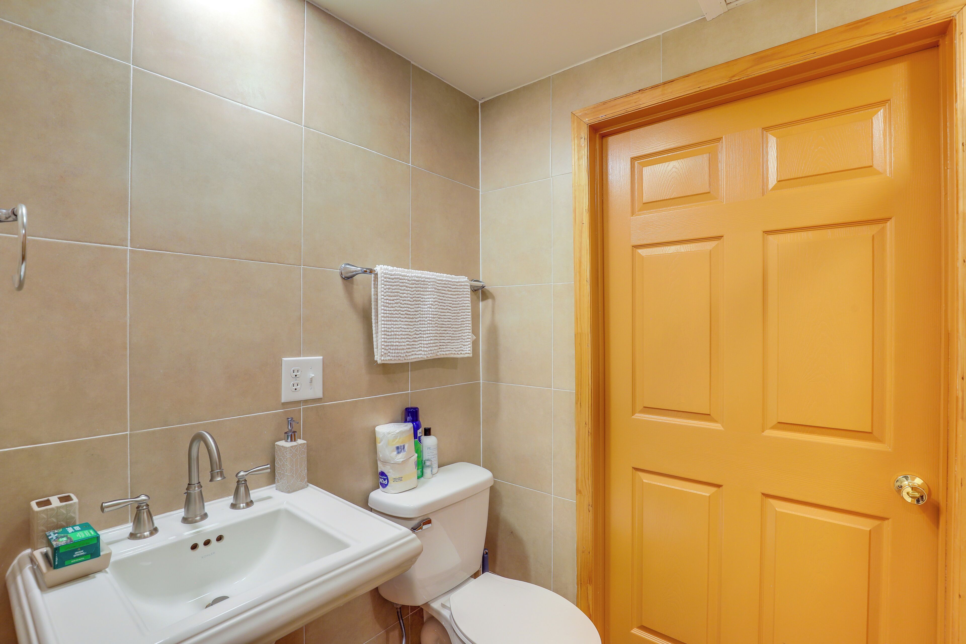Un baño con lavamanos, inodoro y puerta de madera.