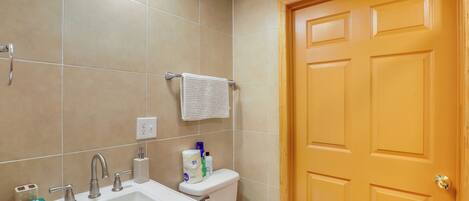Un baño con lavamanos, inodoro y puerta de madera.