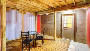 A wooden ceiling with exposed beams, a glass table with chairs, a door, and a stone wall. - Mtn Cabin 1 Mi to Tiec: Outdoor Kitchen + Fire Pit (Mill Spring)