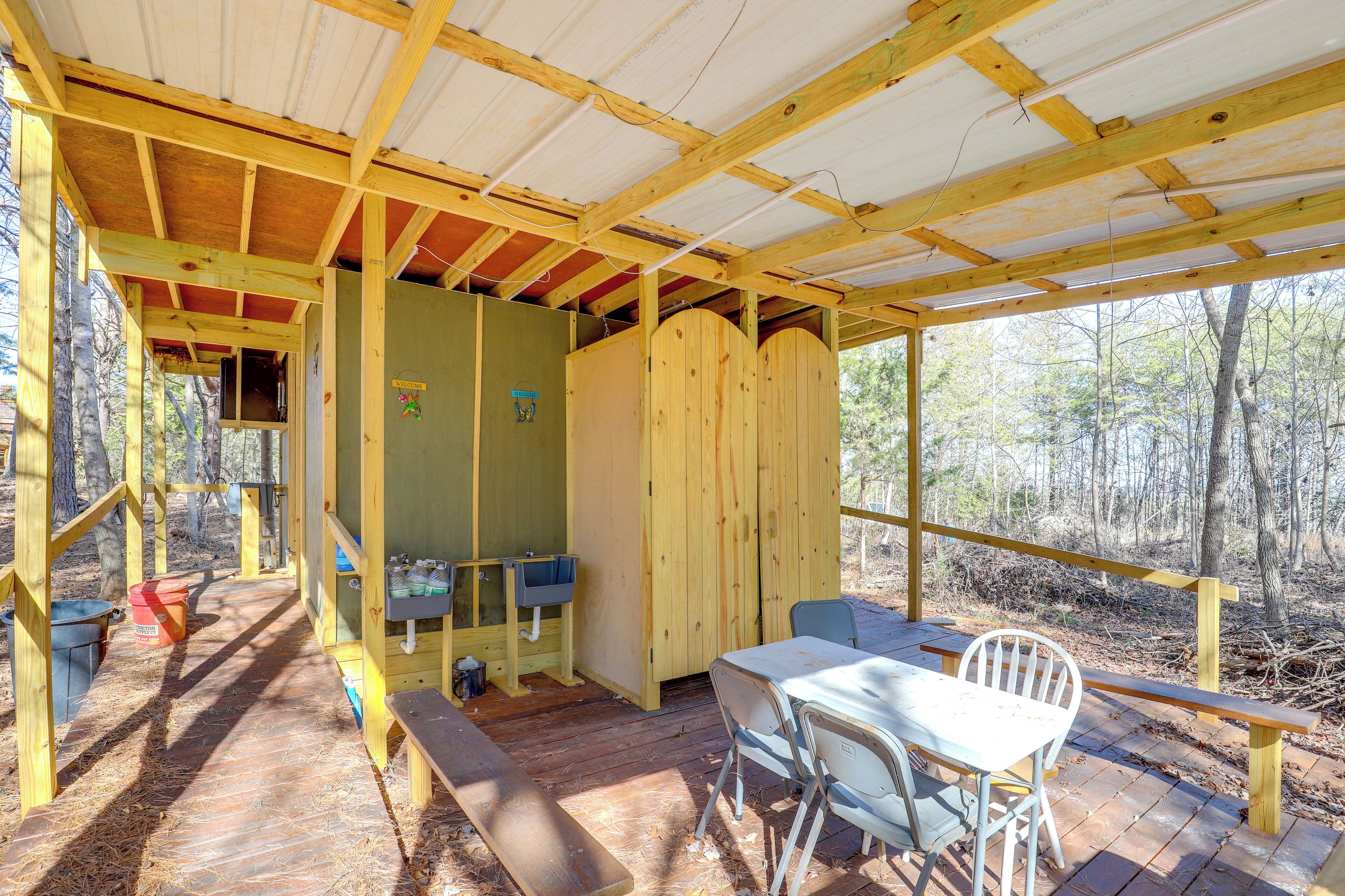 Una terraza de madera con una mesa, sillas, un banco y una zona cubierta con una ventana.