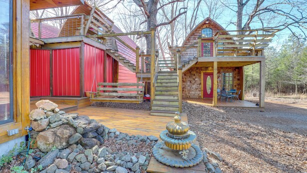 A wooden cabin with a red barn, a wooden deck, and a stone fountain. - Mtn Cabin 1 Mi to Tiec: Outdoor Kitchen + Fire Pit (Mill Spring)