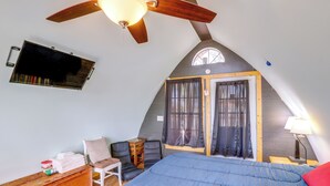 A bedroom with a sloped ceiling, a bed, a chair, a desk, and a window with curtains. - Mtn Cabin 1 Mi to Tiec: Outdoor Kitchen + Fire Pit (Mill Spring)