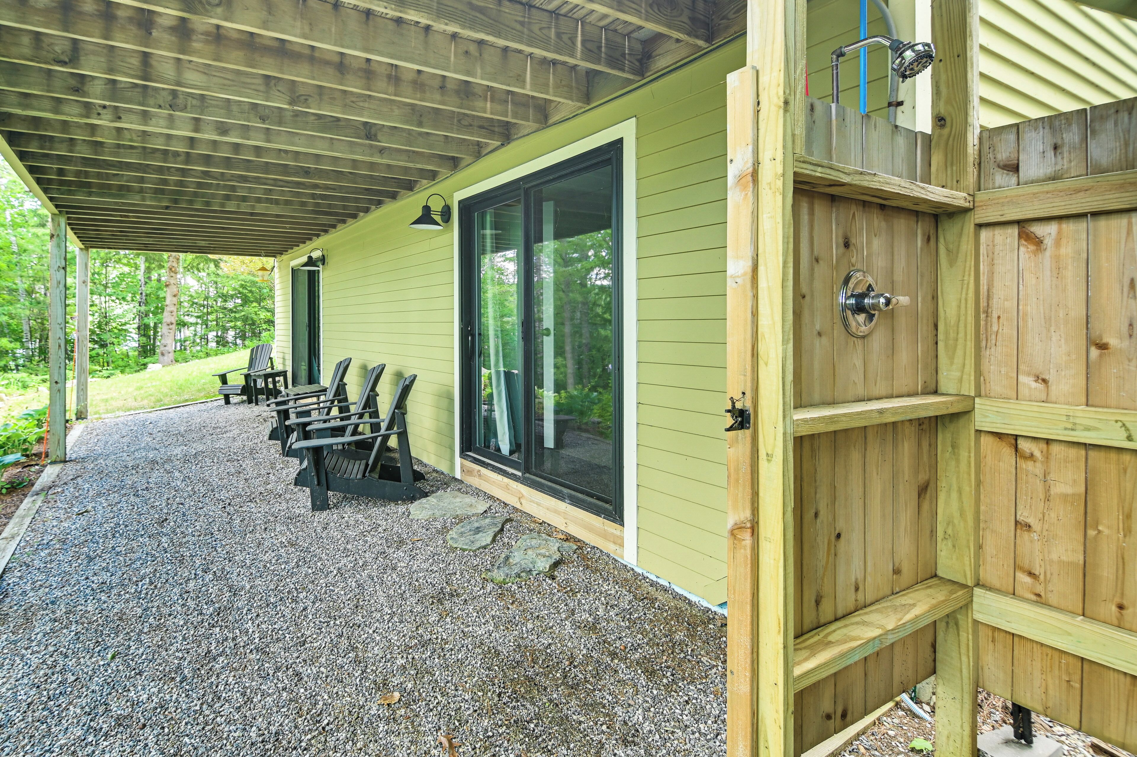 A covered patio with outdoor seating, a wooden door, and a window.