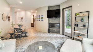 A modern living room with a dining area, a fireplace, and a TV mounted on the wall. - Ski-in/ski-out! Winter Park Family Gem w/ Hot Tub (Winter Park)