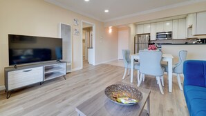 A modern living room with a flat-screen TV, a dining area with a white table and chairs, and a kitchen with white cabinets and appliances. - Tri-valley Getaway 2 Mi to Historic Main Street! (Pleasanton)