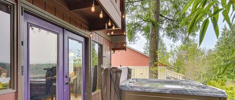 Ein Whirlpool auf einer Holzterrasse mit einer violetten Tür und Fenstern mit Blick auf einen Garten.