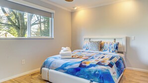 A bedroom with a large window, a bed with a colorful quilt, and a ceiling fan. - 2 Mi to Wineries! Woodinville Home w/ Deck & Yard (Woodinville)