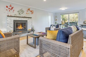 A living room with wicker furniture, a fireplace, and a view of the outdoors. - 2 Mi to Wineries! Woodinville Home w/ Deck & Yard (Woodinville)