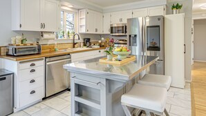A modern kitchen with white cabinetry, a stainless steel refrigerator, a microwave, and a built-in oven. There is a wooden countertop and a small island with a bench. - 2 Mi to Wineries! Woodinville Home w/ Deck & Yard (Woodinville)