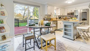 A modern kitchen with white cabinets, a large island, and a sliding glass door leading to a backyard. - 2 Mi to Wineries! Woodinville Home w/ Deck & Yard (Woodinville)