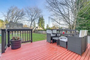 Une terrasse extérieure avec un plancher en bois rouge, des meubles en osier et une plante en pot.