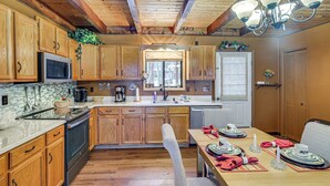 A kitchen with wooden cabinets, a microwave, and a stove. There is a dining table set with plates, cups, and a candle. - Poconos Retreat in The Hideout Lake Community! (Lake Ariel)
