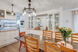 A modern kitchen with white cabinets, a wooden dining table, and a chandelier. - Stunning Mountain Views! Secluded Retreat in Bend (Bend)