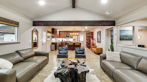 A spacious living area with leather sofas, a central coffee table, and a kitchen in the background. - Private Patio & Yard: Pet-friendly Bulverde Home (Bulverde)