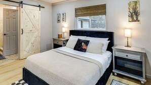 A bedroom with a bed, two bedside tables, a nightstand, a sliding door, and a window with a view. - Private Patio & Yard: Pet-friendly Bulverde Home (Bulverde)