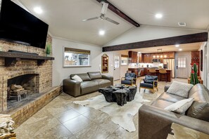 A spacious living room with a fireplace, leather sofas, a coffee table, and a view into the kitchen.