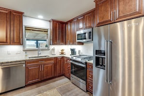 Una cocina con armarios de madera, electrodomésticos de acero inoxidable y un microondas integrado.