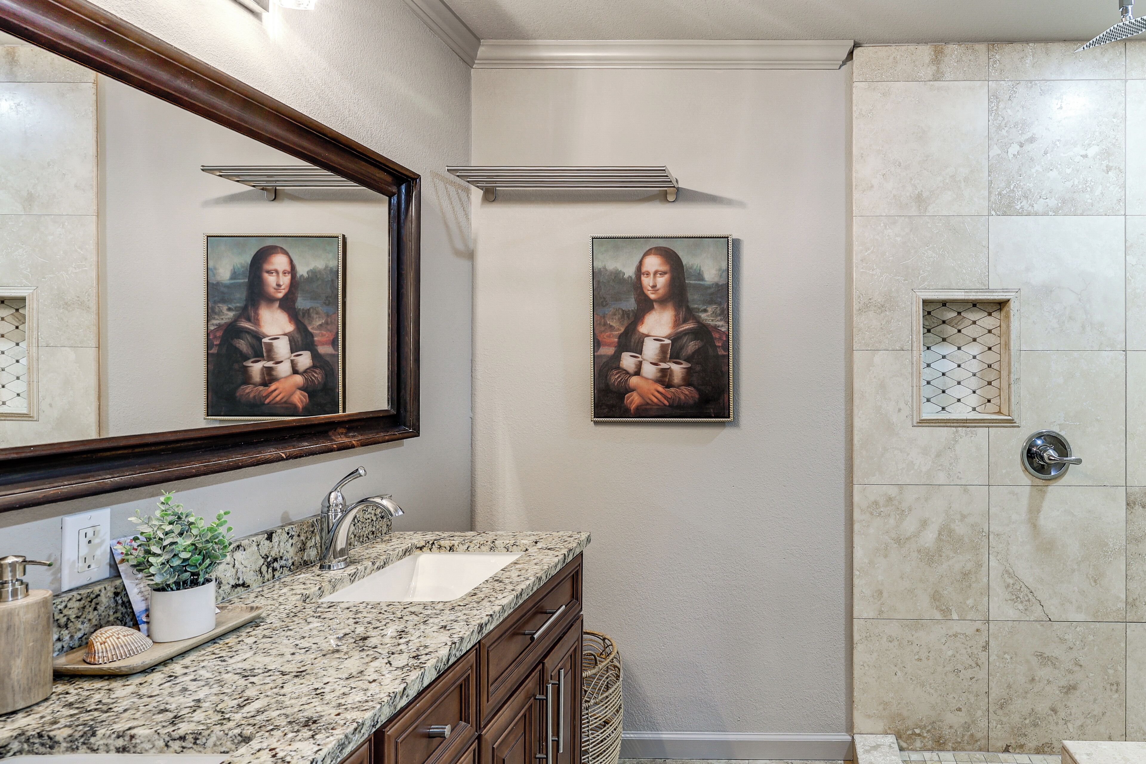 A bathroom with a sink, mirror, and two framed pictures of the Mona Lisa.