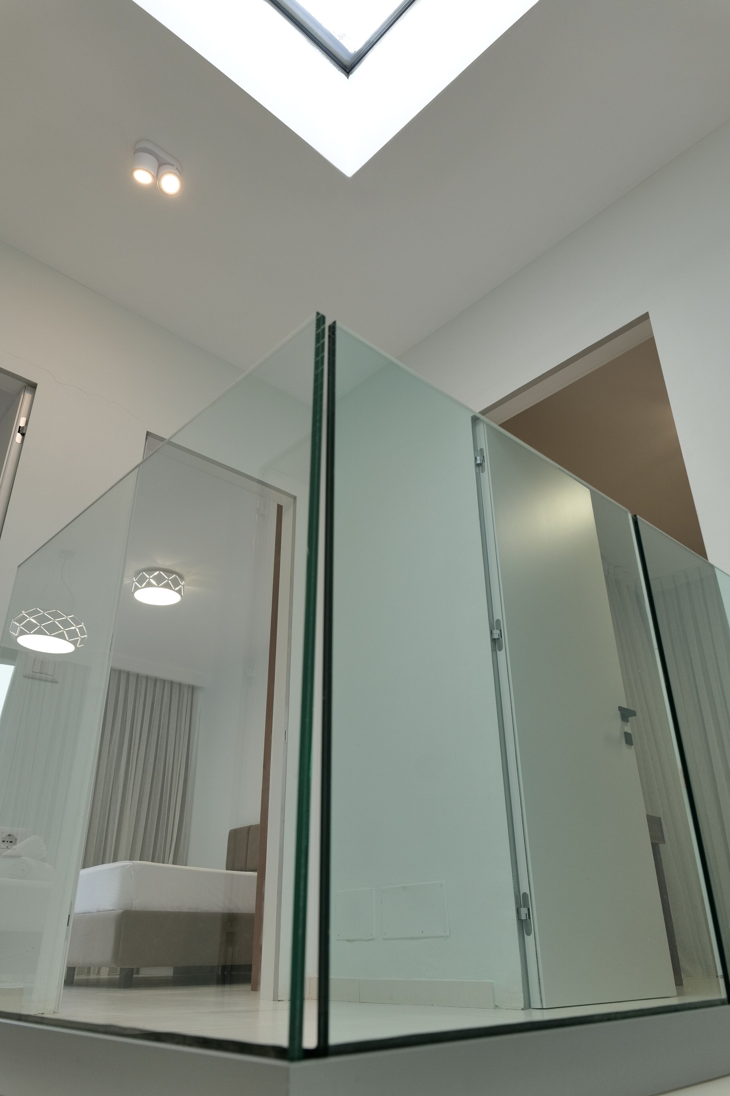 Une chambre moderne avec une cloison en verre, un lit et une lucarne.