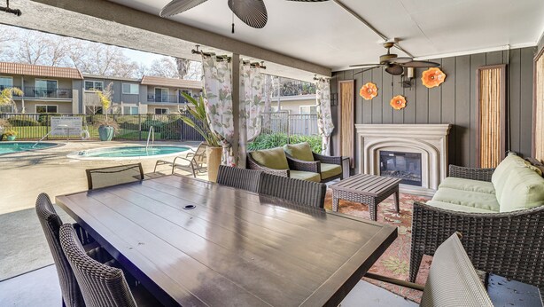 Eine überdachte Terrasse mit Esstisch, Korbmöbeln und Kamin.