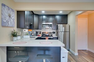 Una cocina moderna con armarios oscuros, electrodomésticos de acero inoxidable y una isla central con taburetes de bar.