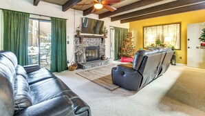 A living room with a fireplace, leather sofas, a ceiling fan, and a Christmas tree. - Nat'l Forest Retreat at 'the Nest at Pinetop' (Pinetop)