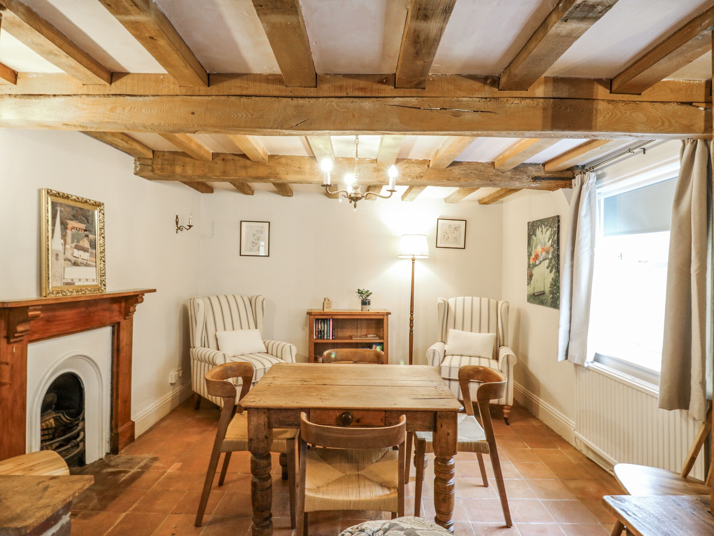 Une pièce chaleureuse avec une table en bois, des chaises, une cheminée et une bibliothèque.