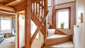 Un escalier en bois, dont les marches sont recouvertes de moquette, mène à un palier.
