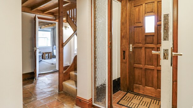 Une porte en bois avec une poignée en métal, un panneau de verre et un paillasson.