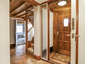 Una porta in legno con maniglia metallica, un vetrino e un tappetino.