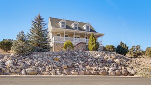 A two-story house with a stone retaining wall, a balcony, and a clear blue sky. - Family & Group Friendly! Hilltop Cedar City Home (Cedar City)