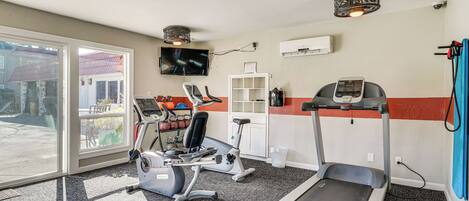 Een sportschool met loopbanden, hometrainers en een gewichtbank.
