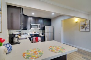 A modern kitchen with dark cabinets, stainless steel appliances, and a white countertop. - Pleasanton Gem in Quiet Community w/ Pool Access (Pleasanton)