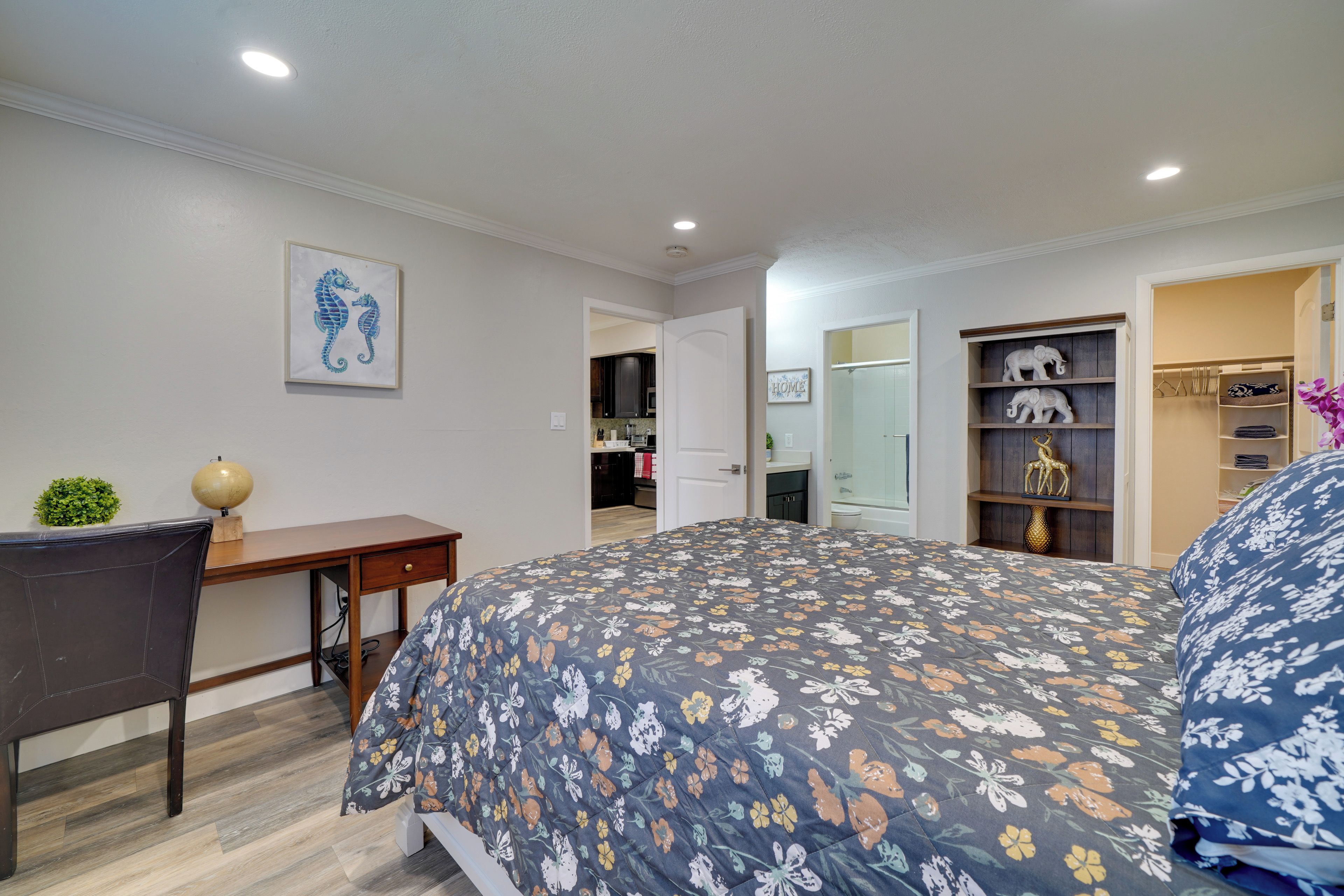 Une chambre à coucher avec un lit, un bureau et une chaise. On y trouve également une armoire et une étagère où sont disposés des objets décoratifs.