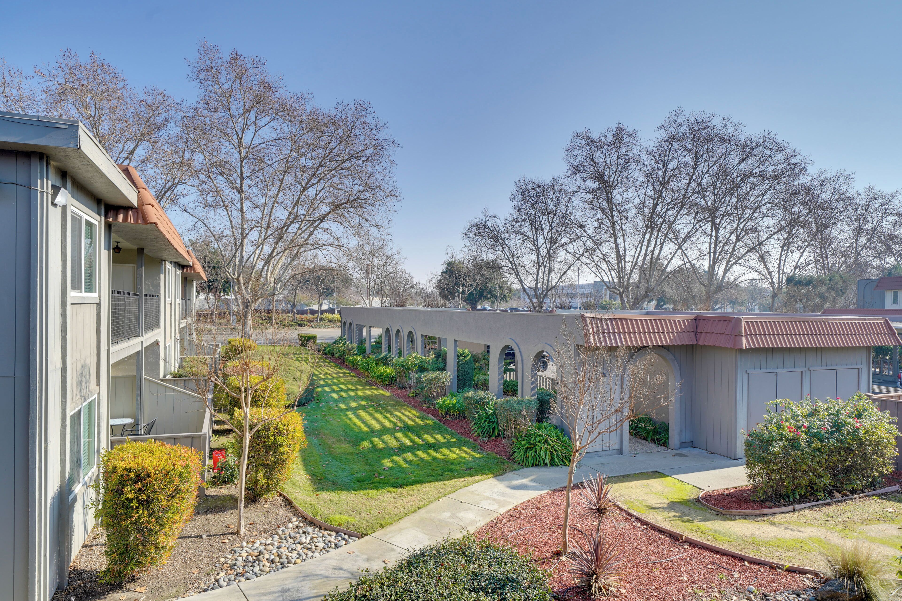 A residential area with a well-maintained lawn, a pathway, and a building with a garage and a covered porch.