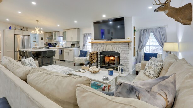 A modern living room with a fireplace, a mounted deer head, and a television.