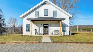 A modern two-story house with a covered porch, large windows, and a gravel driveway. - Peaceful Farmhouse Retreat 6 Mi to Virginia Tech! (Blacksburg)
